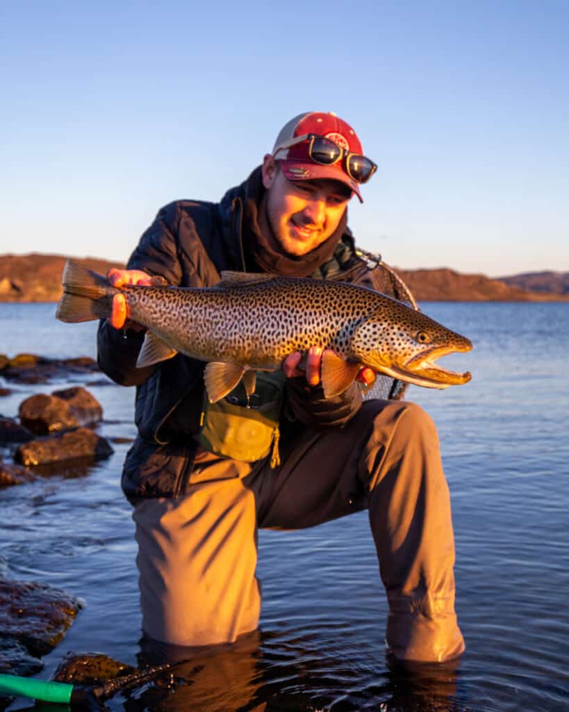 Vibrant fish caught during fishing trip by man in scenic outdoor setting.