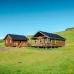 Beautiful wooden cabins on lush green land, ideal for fish farming and aquaculture projects.