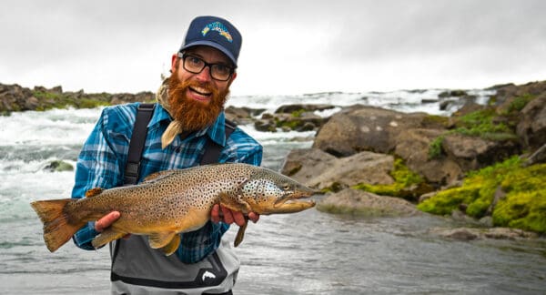 Rainbow trout caught while fishing in natural river landscape.