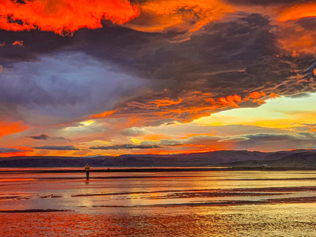 Colorful sunset sky over Vatnamót with a fly-fisherman in the distance.