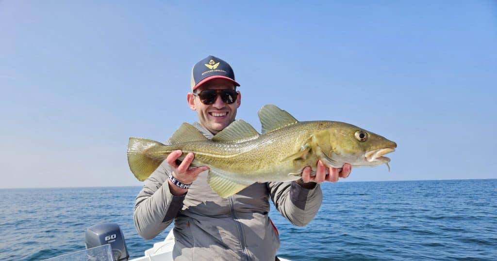 Large freshwater fish caught by smiling angler holding it on a boat in the ocean, promoting fishing and seafood from Fish Partner.