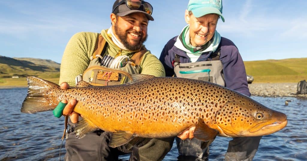 Big rainbow trout caught during fishing trip in scenic river setting.