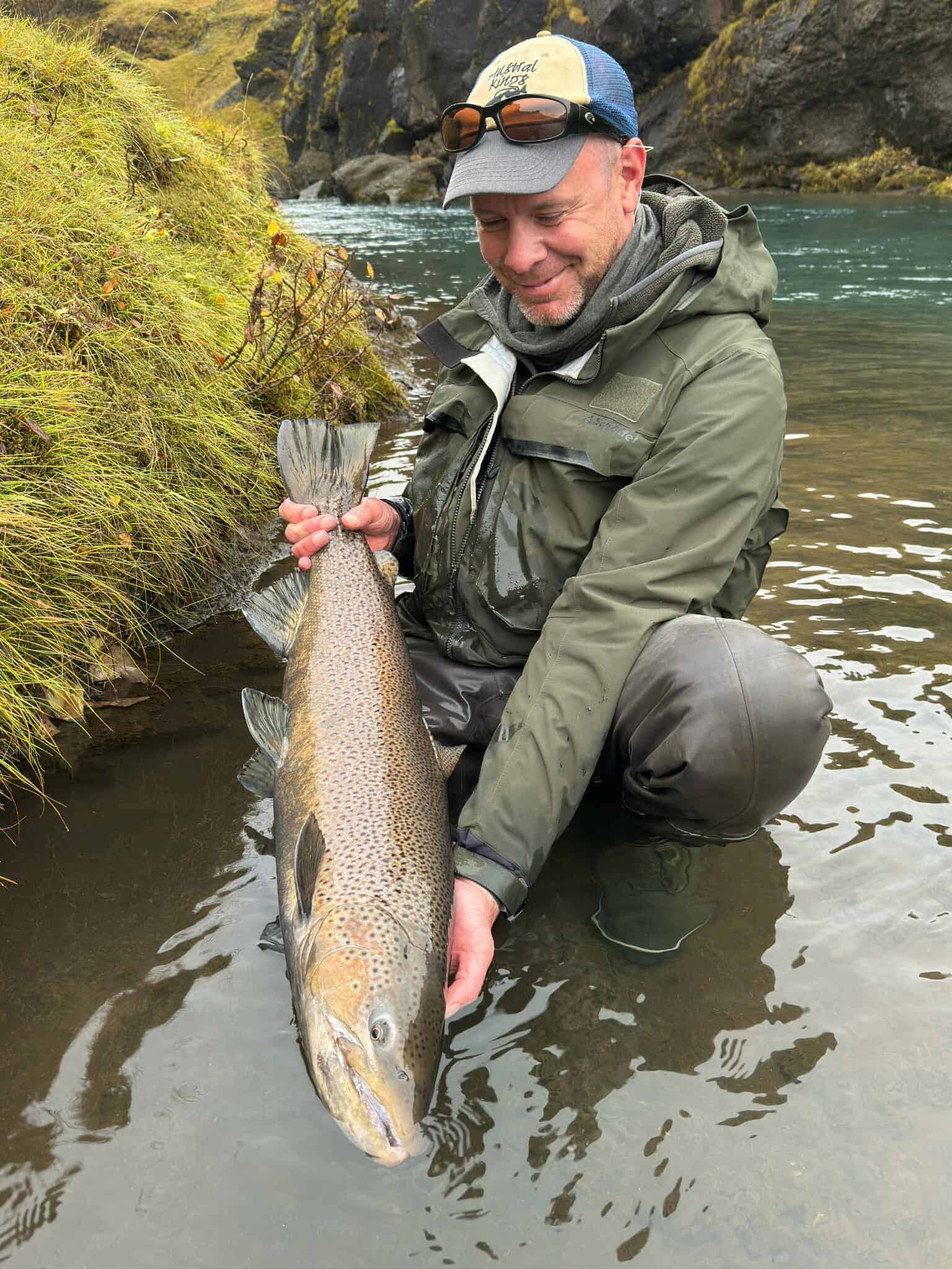 Vibrant rainbow trout caught by angler in scenic river setting. Perfect for fishing enthusiasts and outdoor lovers.