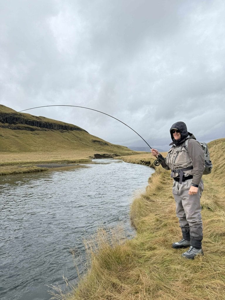 Fishing enthusiast fishing in Iceland's river in heavy weather conditions.