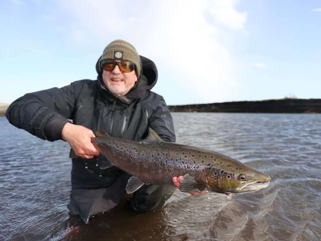 Vibrant large fish caught by an angler in an outdoor river setting, showcasing successful fishing.