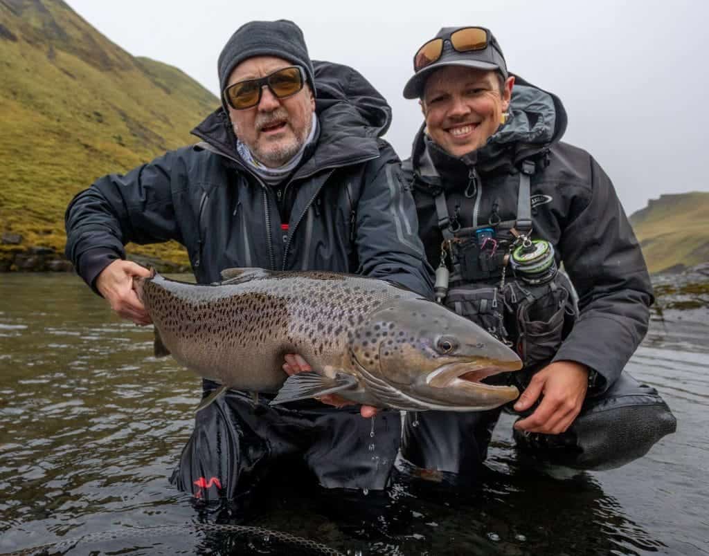 Large rainbow trout caught during a fishing adventure in a scenic river setting.