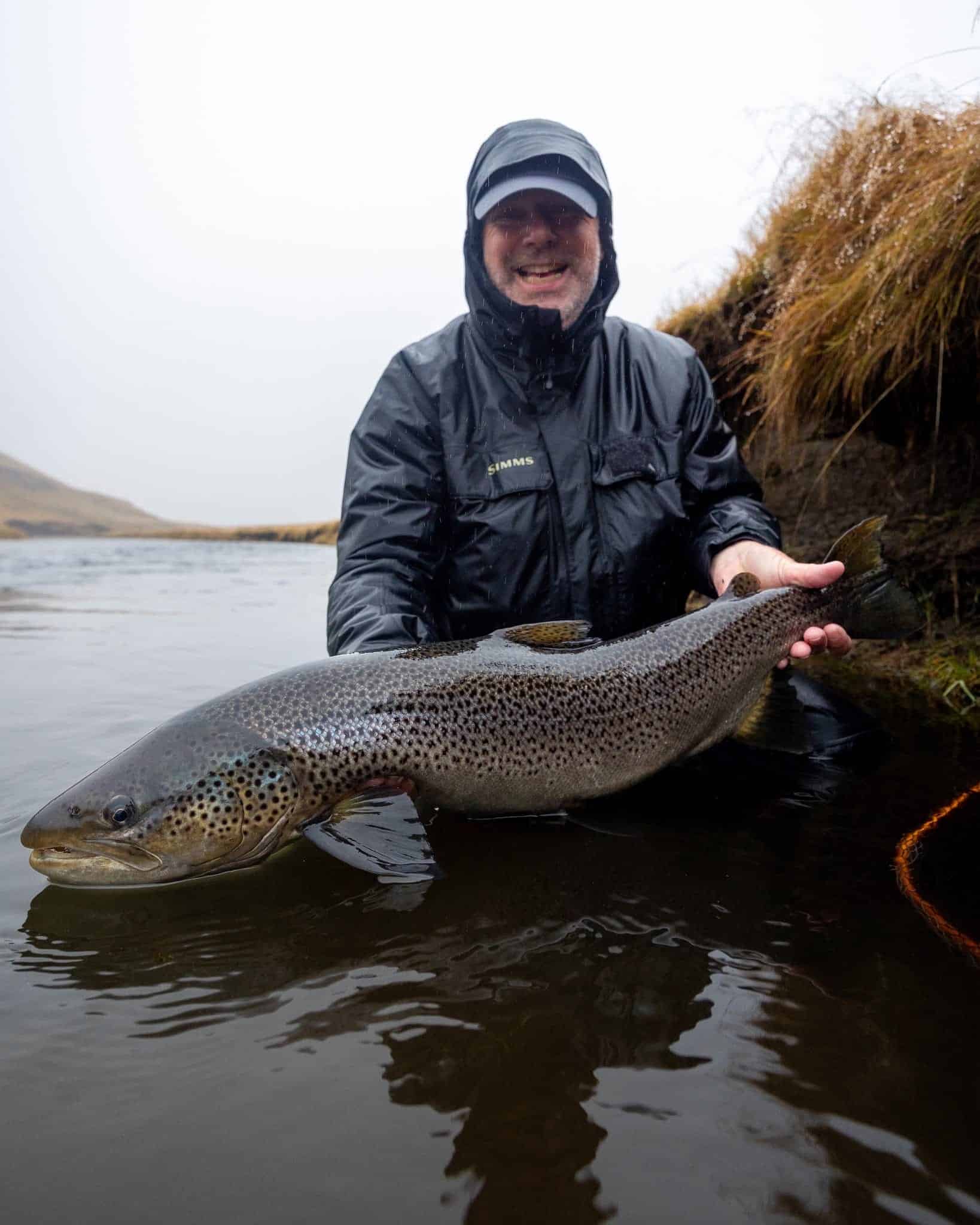 Large rainbow trout caught during fishing trip in natural river setting.