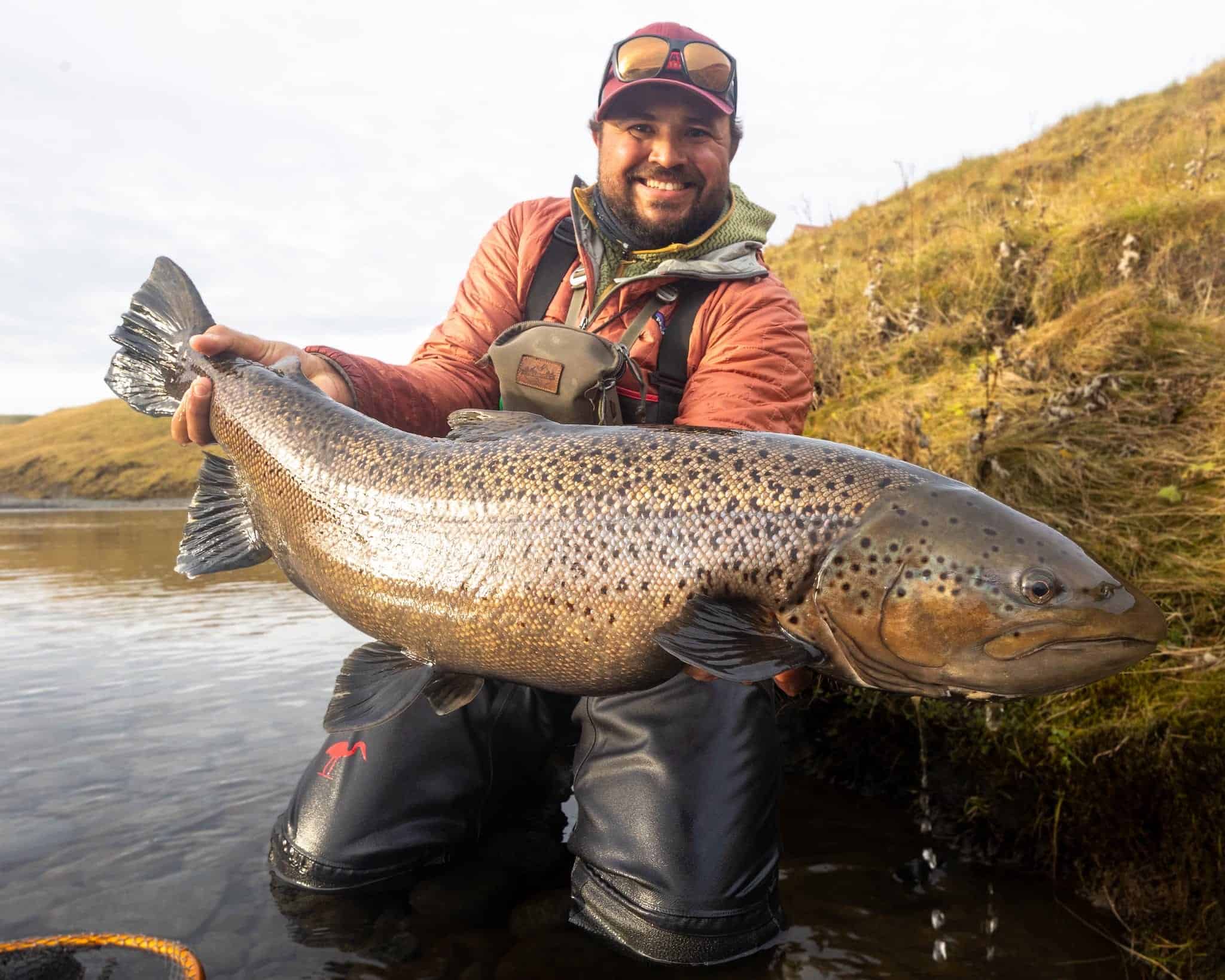 Large fish caught by angler in river, outdoor fishing, rainbow trout, fishing adventure, Fish Partner.