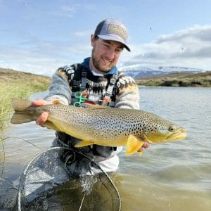 Big rainbow trout caught while fly fishing in Iceland, showcasing expert angling and stunning natural scenery.