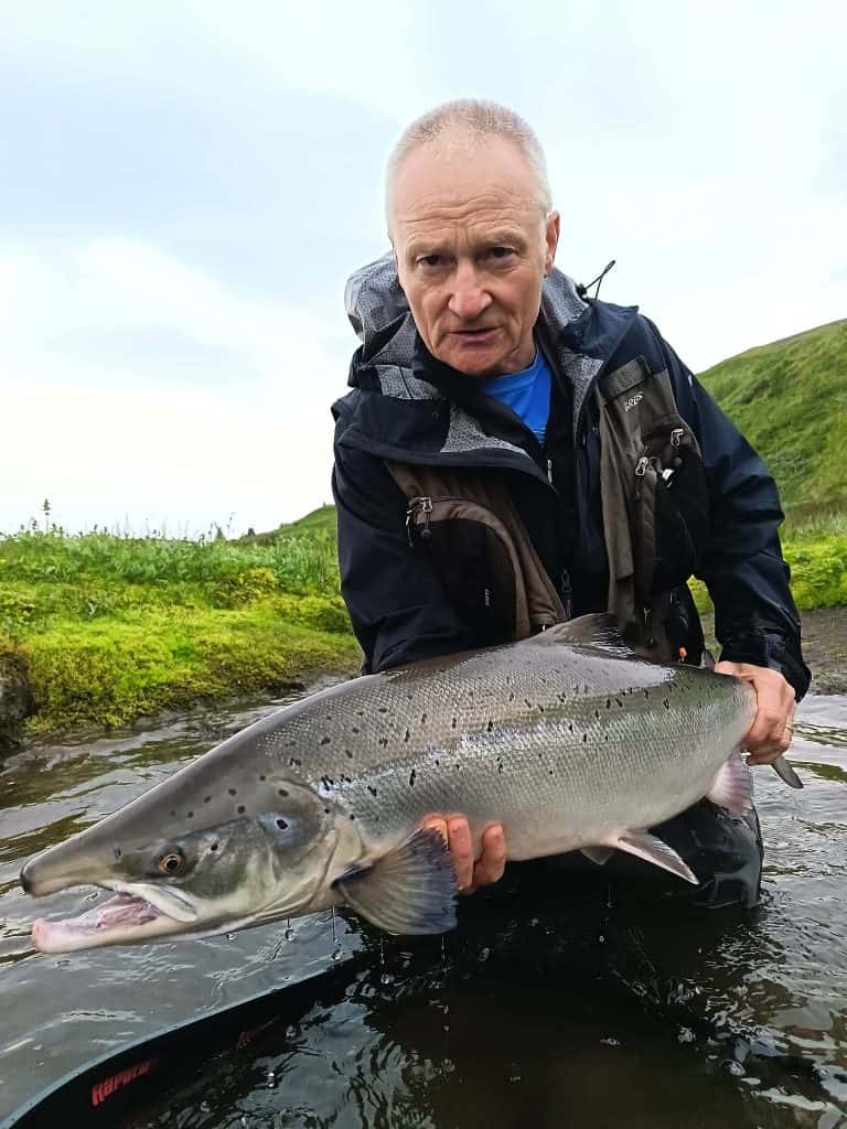 Man holding a large sea run brown trout in a river.