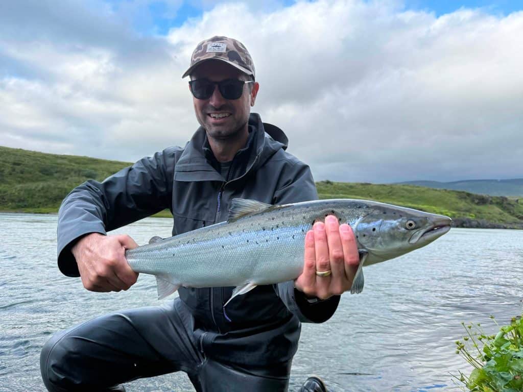 Man holding a sea run brown trout by the river.
