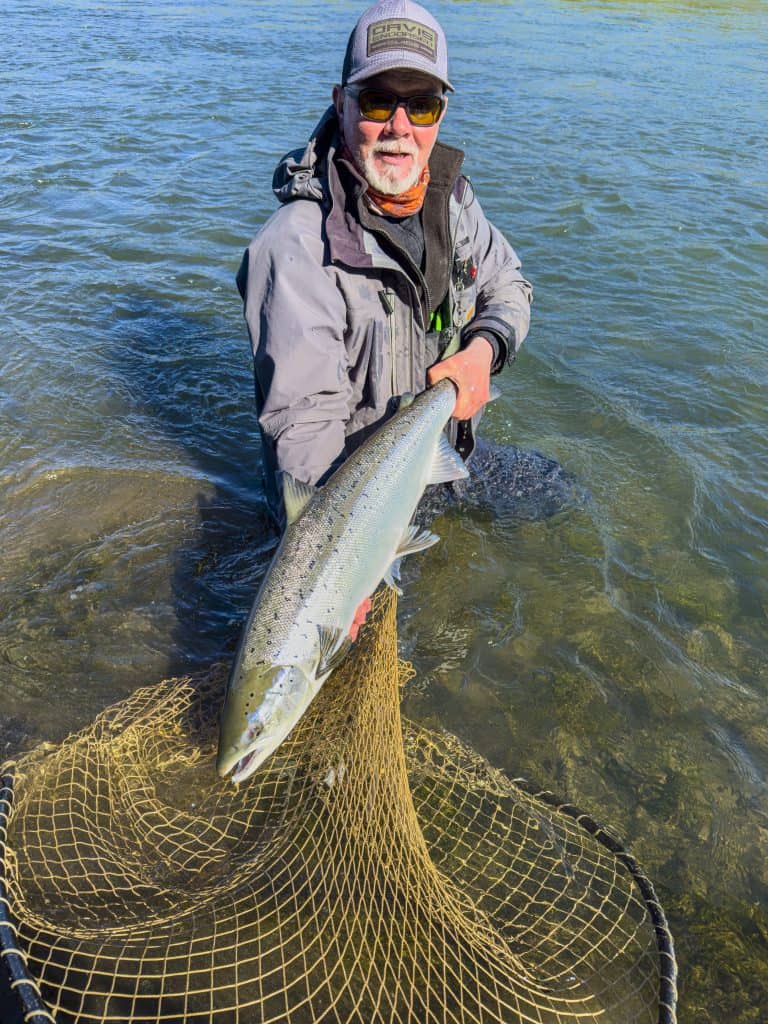 Fisherman holding a large fish in clear water during a fishing trip.