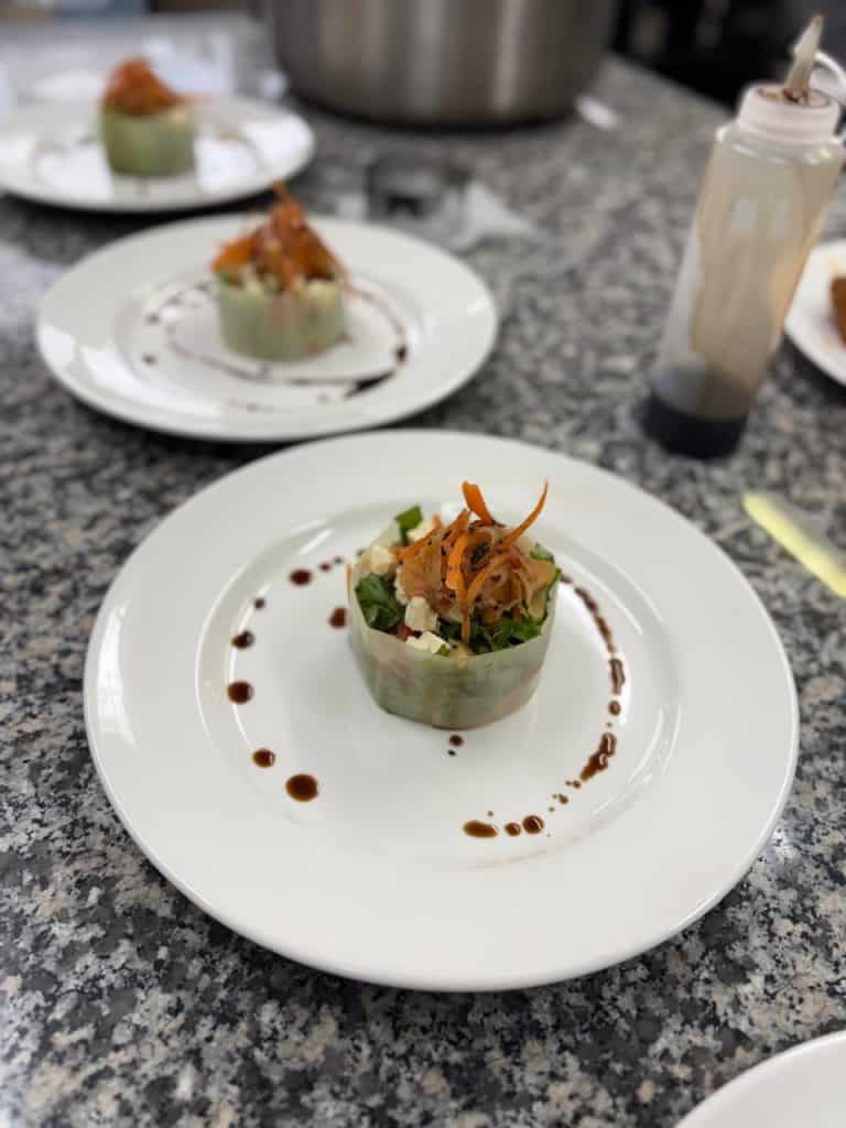 Elegant fish dish with vegetables and sauce on a white plate.