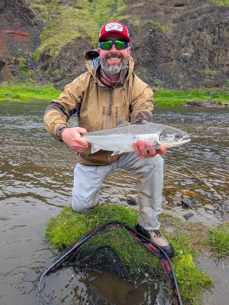 Angler holding a sea run brown trout in a river setting.