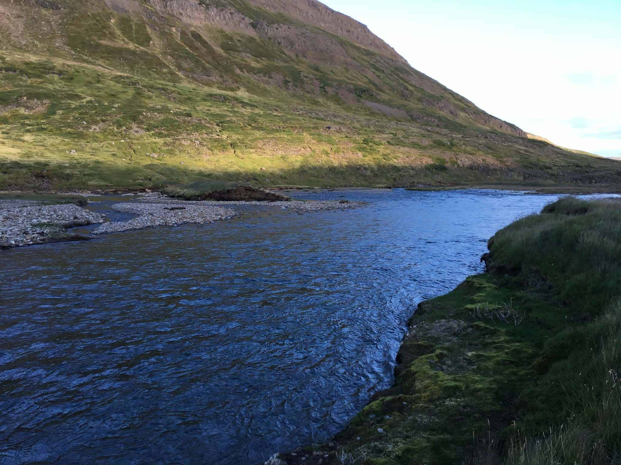 Beautiful river scene with green hills and mountain in the background.