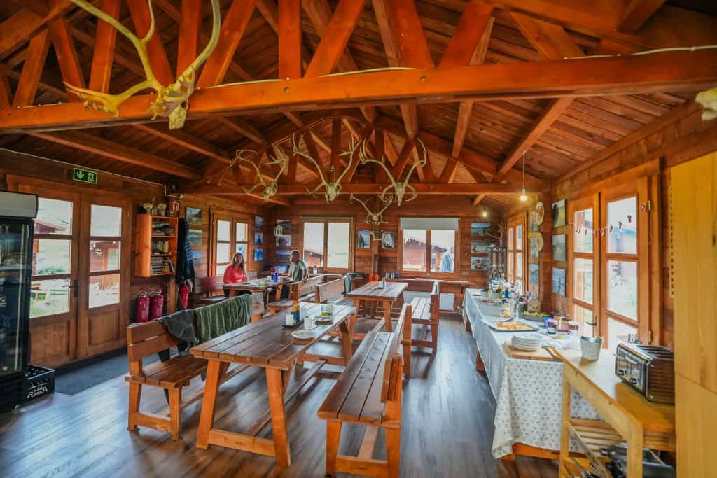 Cozy wooden lodge interior with dining tables and windows.