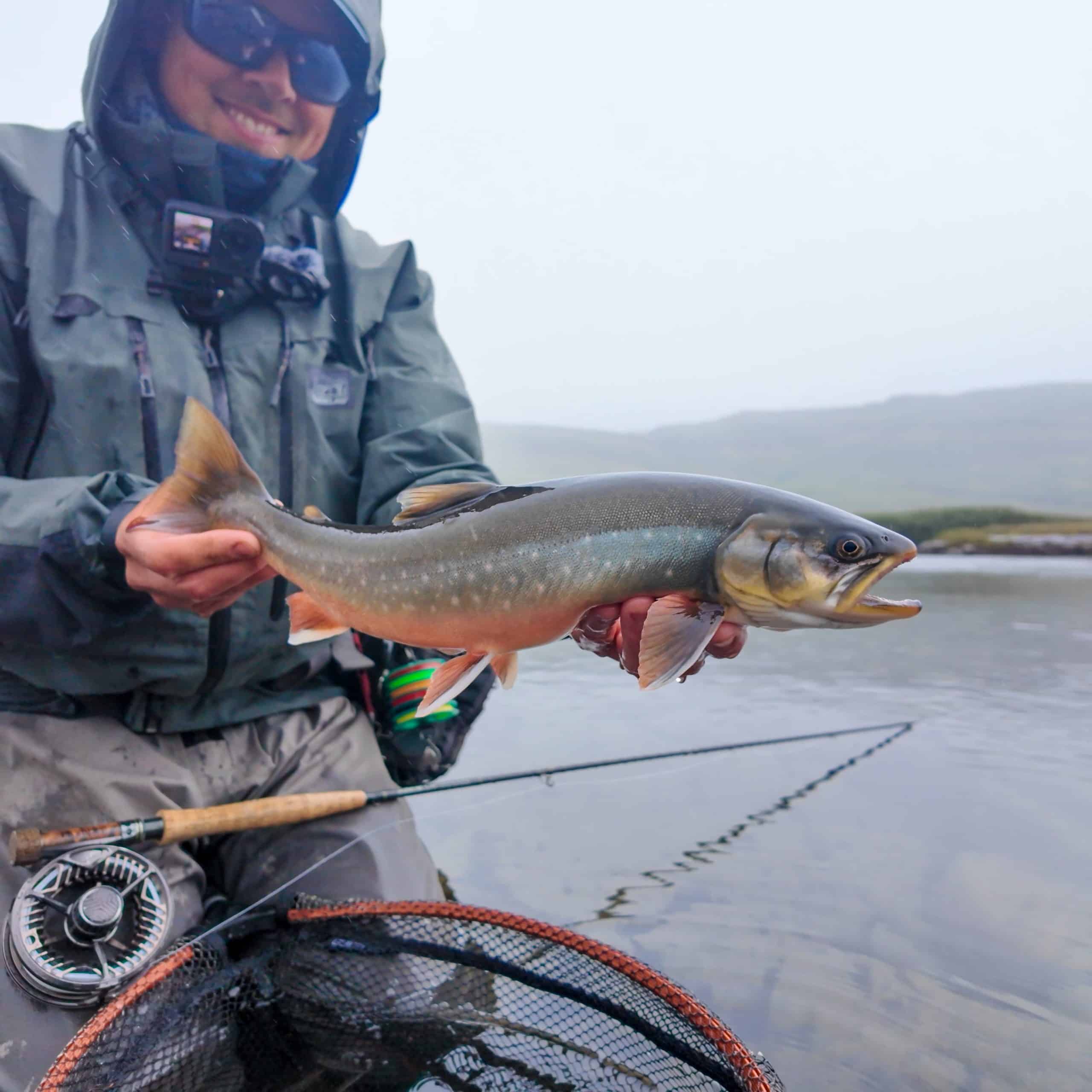 Angler holding a large fish in a river during fishing trip.