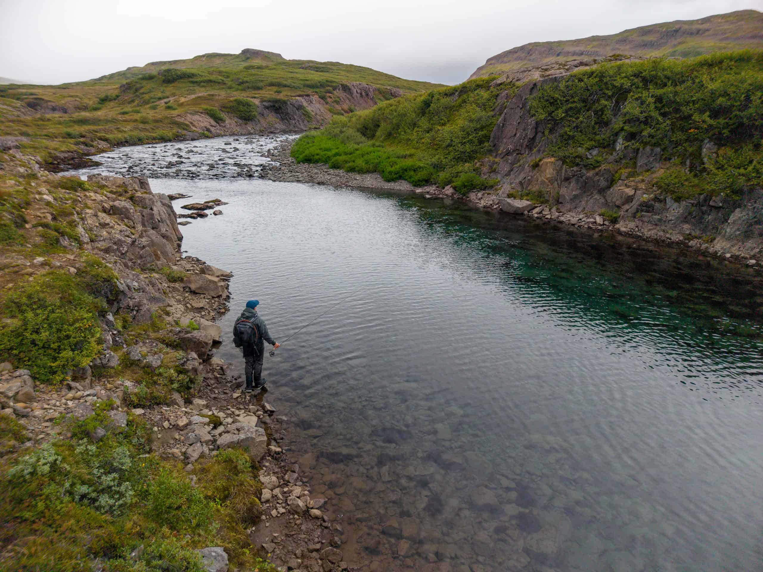Fisherman standing by the riverbank in Bjarnarfjarðará for Arctic Char fishing.