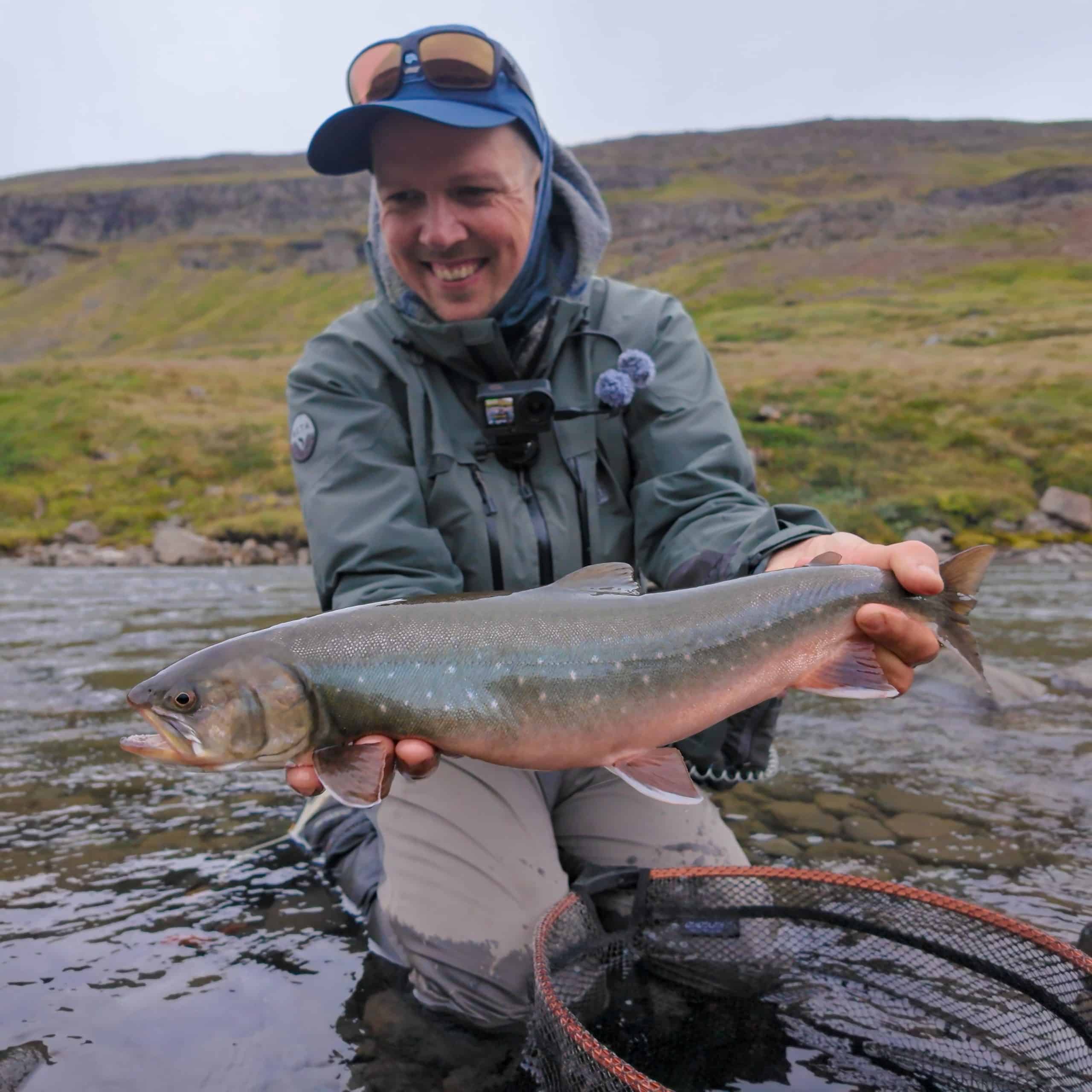 Angler holding a fish in the river during fishing trip.