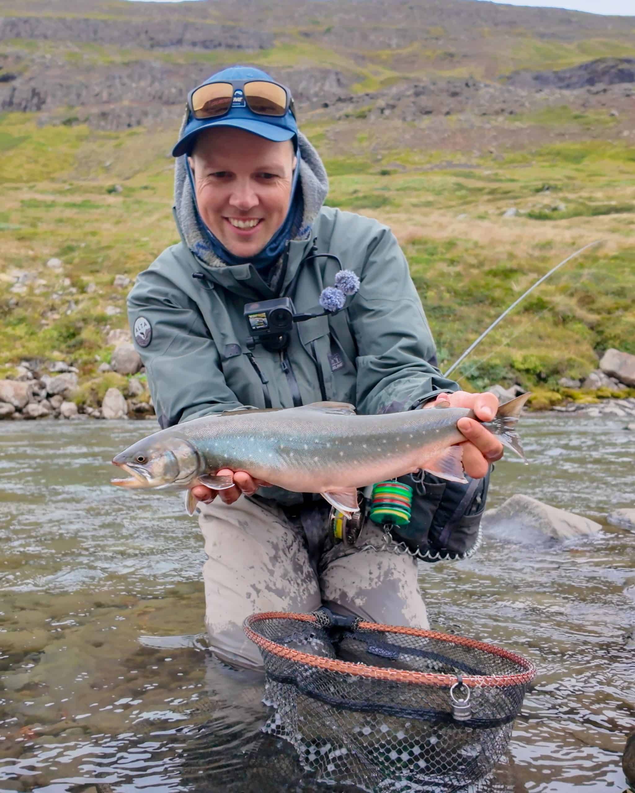 Angler holding a fish in the river during a fishing trip.