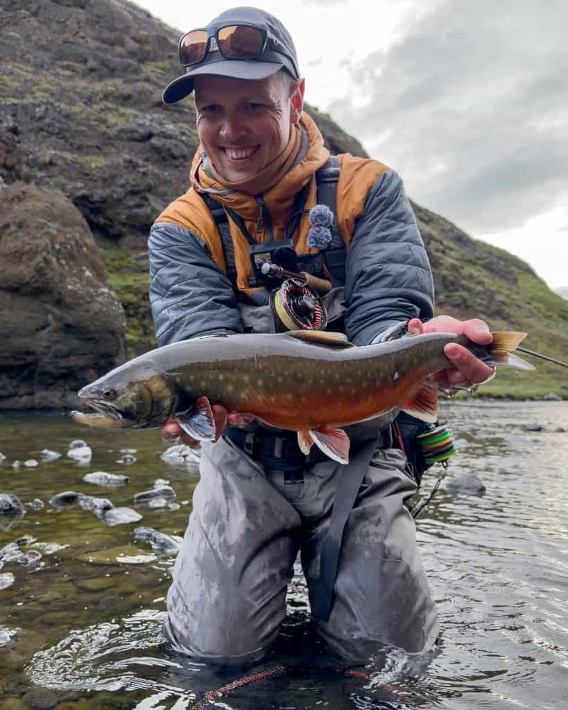 Angler holding a freshly caught fish in a river.