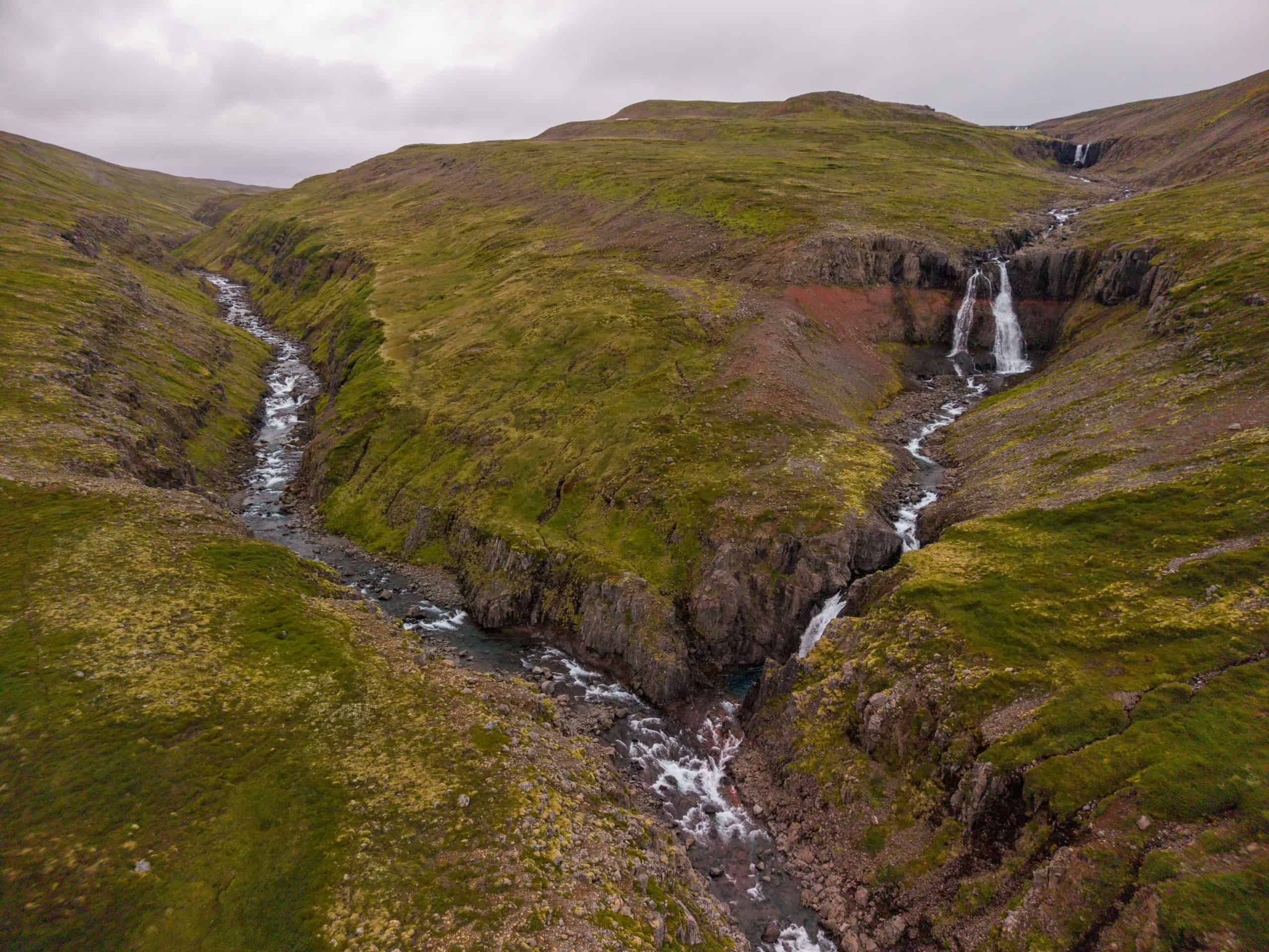 Beautiful landscape of the Goðdalsá river with waterfalls and green hills.