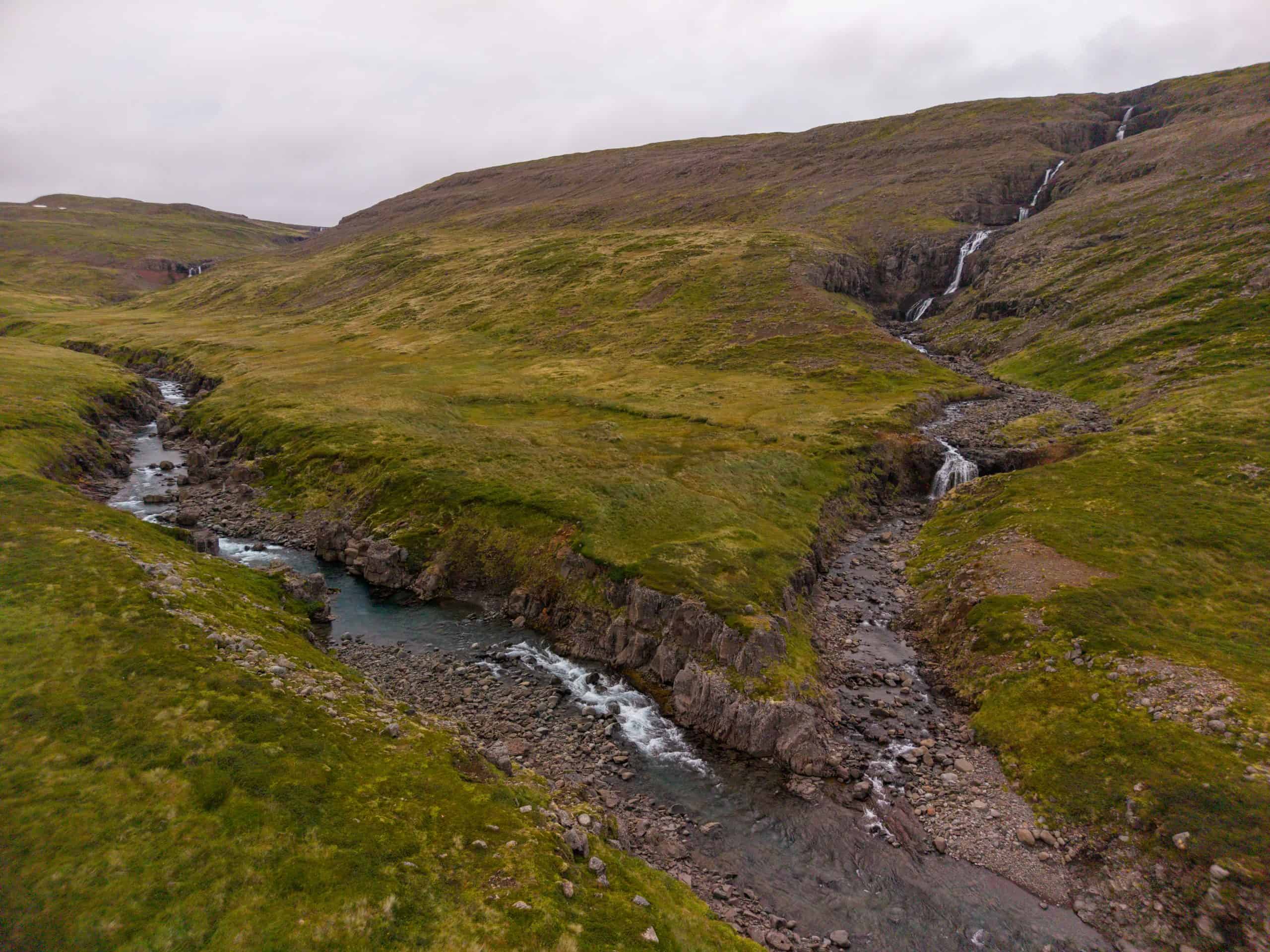 Beautiful landscape of the Goðdalsá river flowing through green hills.