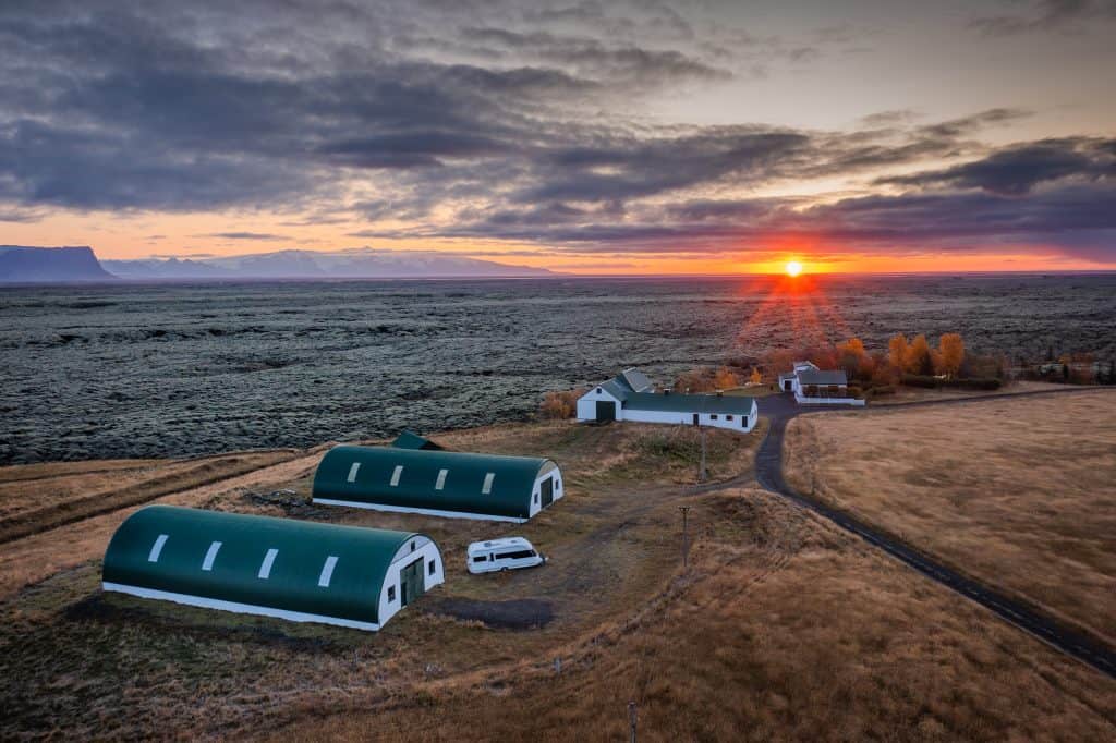 Icelandic fishing lodges at sunset with dramatic sky and open landscape.