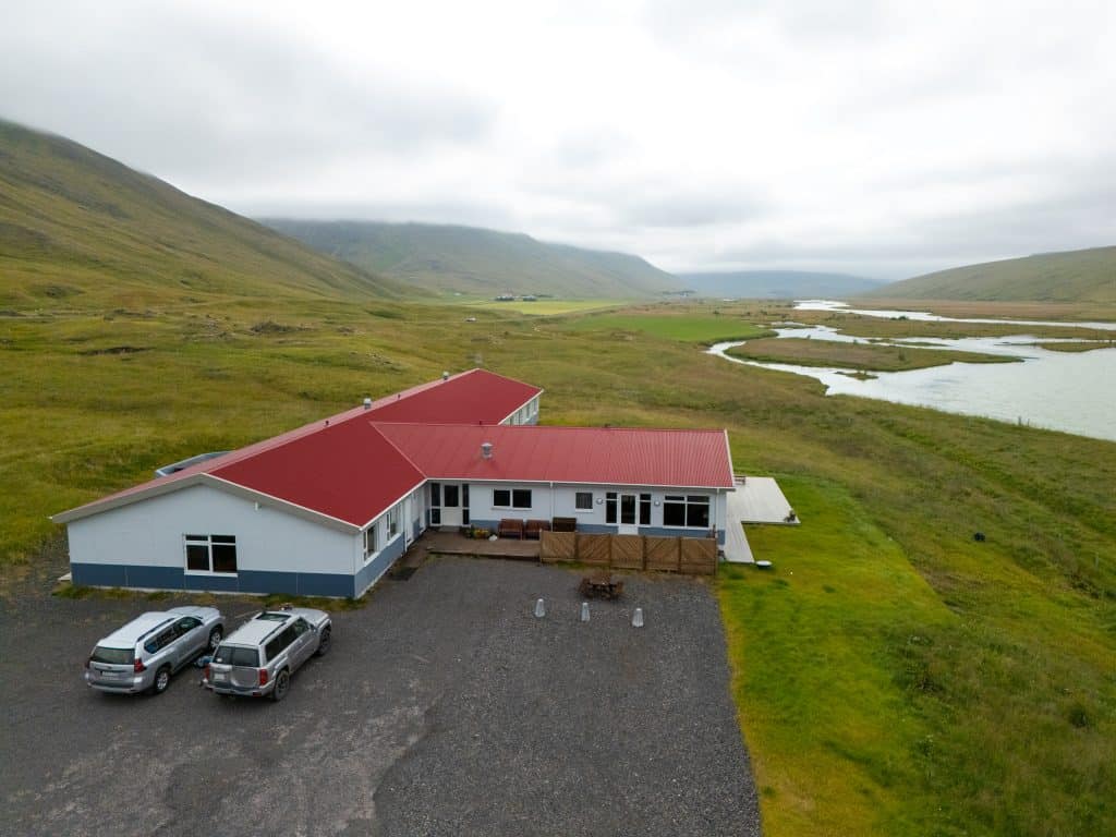 Aerial view of a lodge with red roof near river in Iceland.
