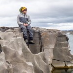 Man sitting on canyon wall next to river