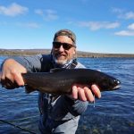 Large fish caught during a fishing trip in a scenic outdoor location. Big catch of a freshwater fish caught by an angler standing in a river on a sunny day.