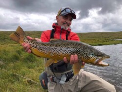 Fly fisherman holding a brown trout