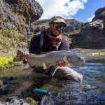 Enjoy a successful day fly fishing for rainbow trout in scenic mountain streams. Vibrant rainbow trout caught in mountain stream by smiling angler, showcasing high-quality fly fishing experience.