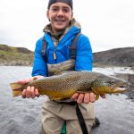 Fishing enthusiast showing off his impressive rainbow trout catch. Rainbow trout caught during fishing adventure in natural river setting.
