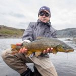 Caught a big fish during a fishing trip in a scenic outdoor river setting. Fish partner, fishing, catch and release, trout fishing, outdoor angling, river fishing, fly fishing, fisherman holding fish, scenic river backdrop, sport fishing.