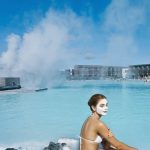 Visitors relaxing in a luxurious geothermal hot spring pool with scenic mountain views and therapeutic waters. Hot spring pool with steaming geothermal water and relaxing woman in spa setting.