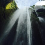 Stunning waterfall surrounded by vibrant moss and greenery in a serene natural setting. Waterfall cascading down moss-covered rocks in a lush green canyon.