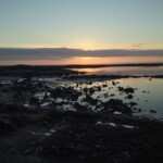 Scenic sunset at the coast highlighting aquaculture potential and marine ecosystem health. Sunset over rocky coastal waters, ideal for fish farming and aquaculture investment.