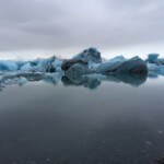 Majestic glacier icebergs floating in the Arctic Ocean create a stunning polar landscape with cold, icy waters and floating ice chunks. Glacier ice floating in Arctic sea water, cold environment, sea icebergs, polar landscape, frozen ocean scene, icy waters, melting ice blocks.