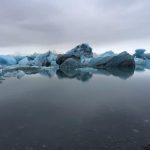 Majestic glacier icebergs floating in the Arctic Ocean create a stunning polar landscape with cold, icy waters and floating ice chunks. Glacier ice floating in Arctic sea water, cold environment, sea icebergs, polar landscape, frozen ocean scene, icy waters, melting ice blocks.