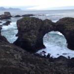 Scenic coastal landscape showcasing volcanic rocks and ocean waves in Iceland. Weathered rock formations and natural ocean arch at the Icelandic coastline.