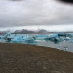 Stunning iceberg landscape in Iceland with floating ice formations and snow-capped mountains, ideal for showcasing cold water and environmental conservation. Icebergs floating in glacial lake under cloudy sky, Iceland snow-capped mountains, cold environmental scenery, Fish Partner.