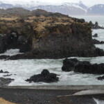 Stunning Icelandic coastline showcasing volcanic rock formations and ocean waves, ideal for sustainable fish sourcing. Rocky coastal landscape with volcanic formations and ocean waves, Iceland - Fish Partner.
