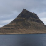 Majestic mountain peak overlooking a tranquil lake, emphasizing Icelandic natural beauty and landscape photography. Serene mountain landscape with dramatic steep slopes and a calm water body in the foreground.