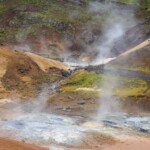 Vivid geothermal landscape in Iceland with steam vents and vibrant mineral deposits, highlighting volcanic activity and natural beauty. Geothermal area with steam vents and mineral deposits, Iceland volcanic landscape.