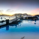 Relaxing hot spring geothermal pool surrounded by scenic mountains with steam rising at sunrise or sunset. Hot spring geothermal pool with scenic mountain view and steam at sunrise or sunset.