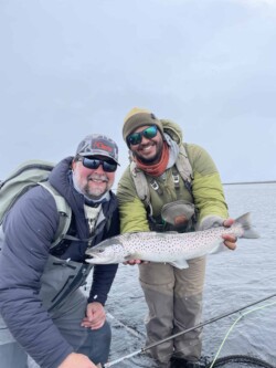 Enjoy a successful fishing adventure with premium fish from Fish Partner. A large trout caught during a fishing trip, shared by two smiling anglers in outdoor gear.